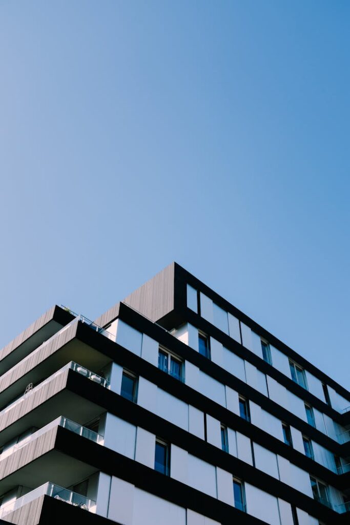 pexels-photo-3709341 Low angle view of a modern apartment building with sleek design against a clear blue sky.