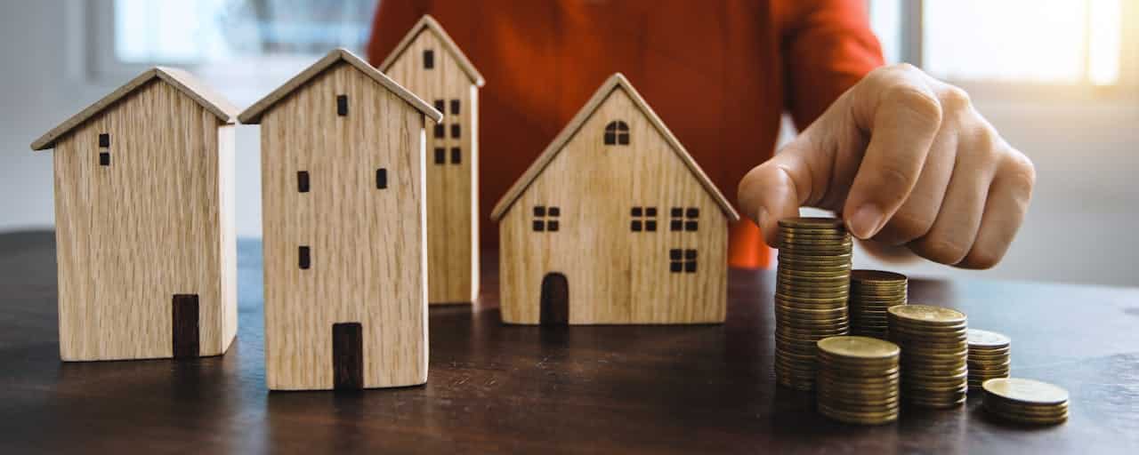 pexels-photo-4174740 Planning investments with stacked coins and model houses on a table.