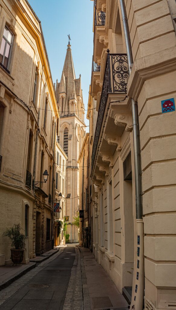 pexels-photo-32784617-32784617 Beautiful narrow street leading to a historic church in Montpellier, France. Perfect for travel enthusiasts.